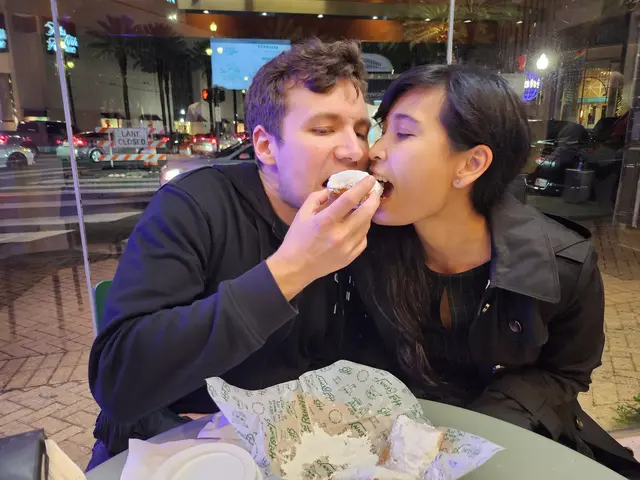 Chris and Emily bite into the same beignet