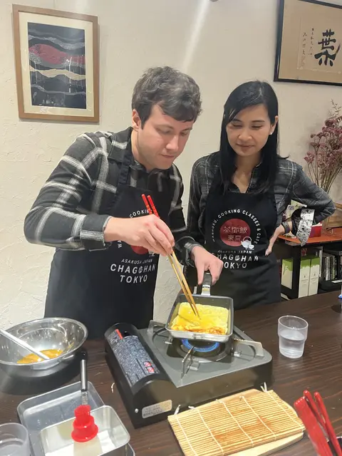 Emily watches as Chris folds tamago at a cooking class